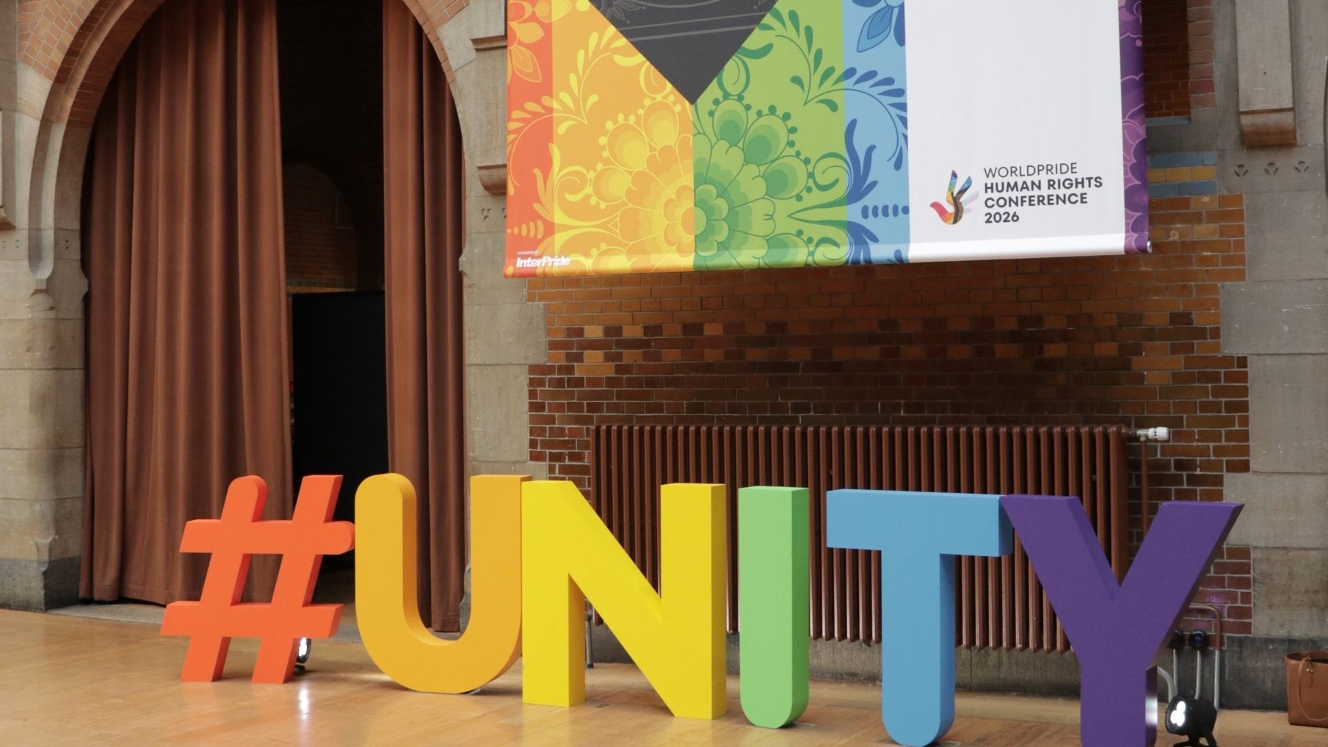 Colourful UNITY installation beneath a WorldPride Human Rights Conference 2026 banner in Amsterdam